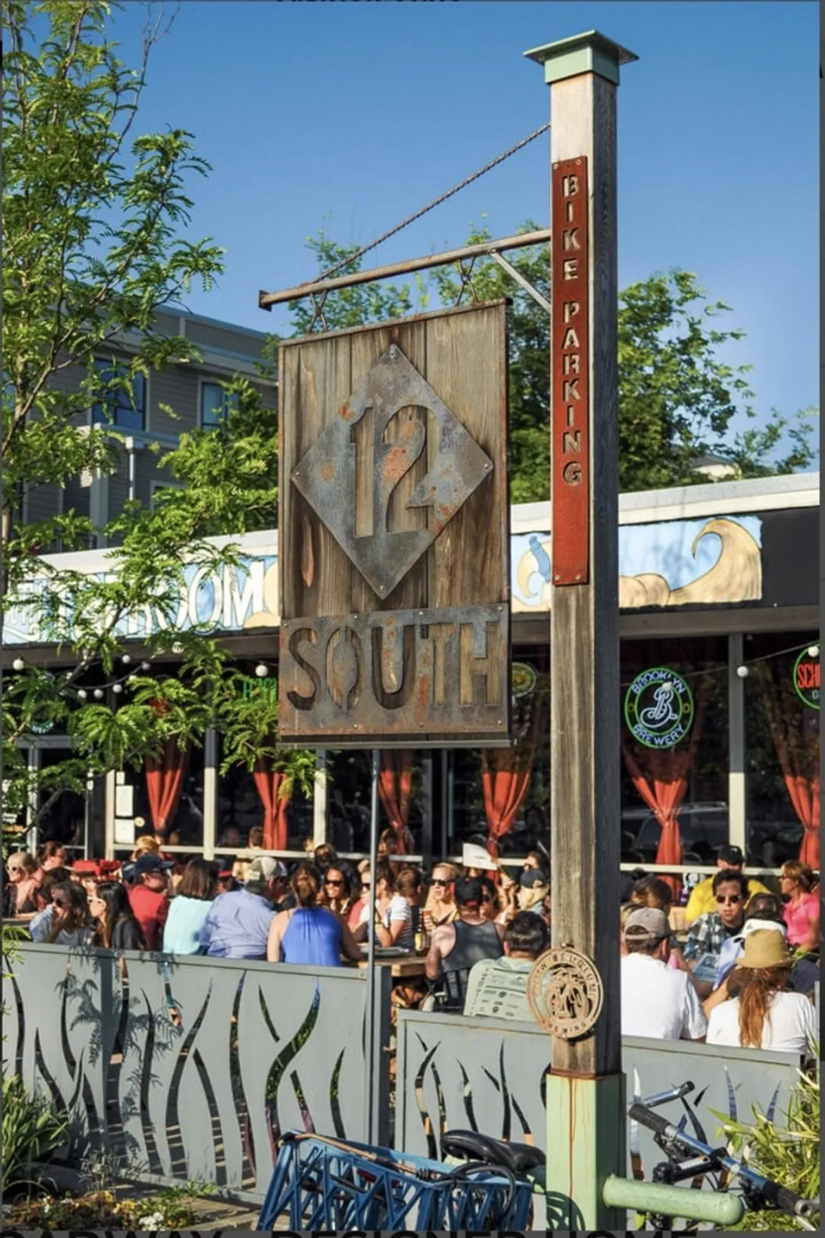 This image features the welcoming 12 South sign and people dining outdoors, surrounded by bike parking and a casual, bustling ambiance. The scene captures the trendy, community-oriented vibe of one of Nashville’s popular neighborhoods, inviting exploration and local flavor.