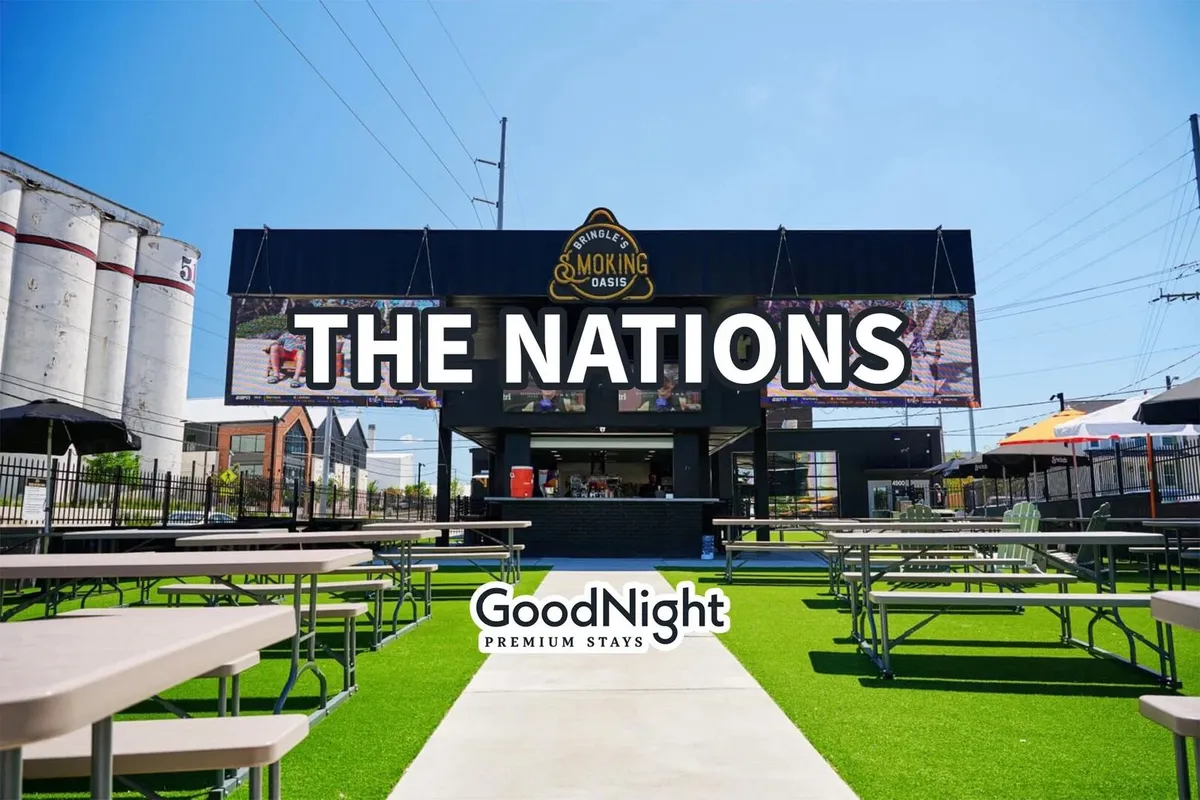 An outdoor dining area with a prominent 'THE NATIONS' sign and a lively food kiosk, surrounded by people enjoying meals and gatherings. The communal atmosphere showcases the social aspect of Nashville’s food destinations.