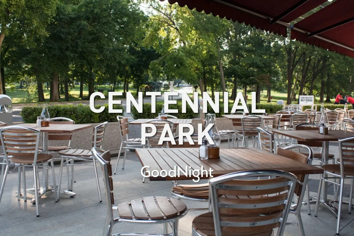An outdoor seating area set among green trees, with wooden tables and cheerful, relaxed atmosphere. This scene invites group dining, socializing, or simply unwinding with friends and family in a natural, communal setting.